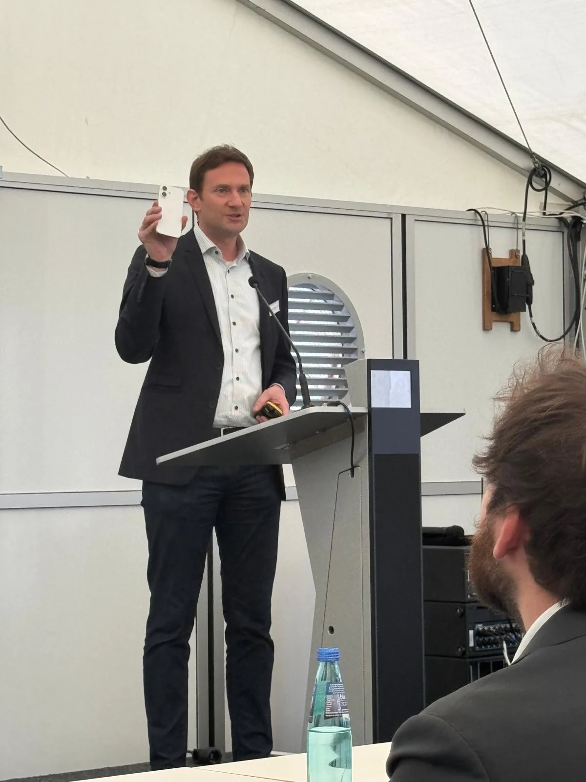 Referent zeigt ein Smartphone am Rednerpult beim Innovation Forum Medizintechnik in Tuttlingen.